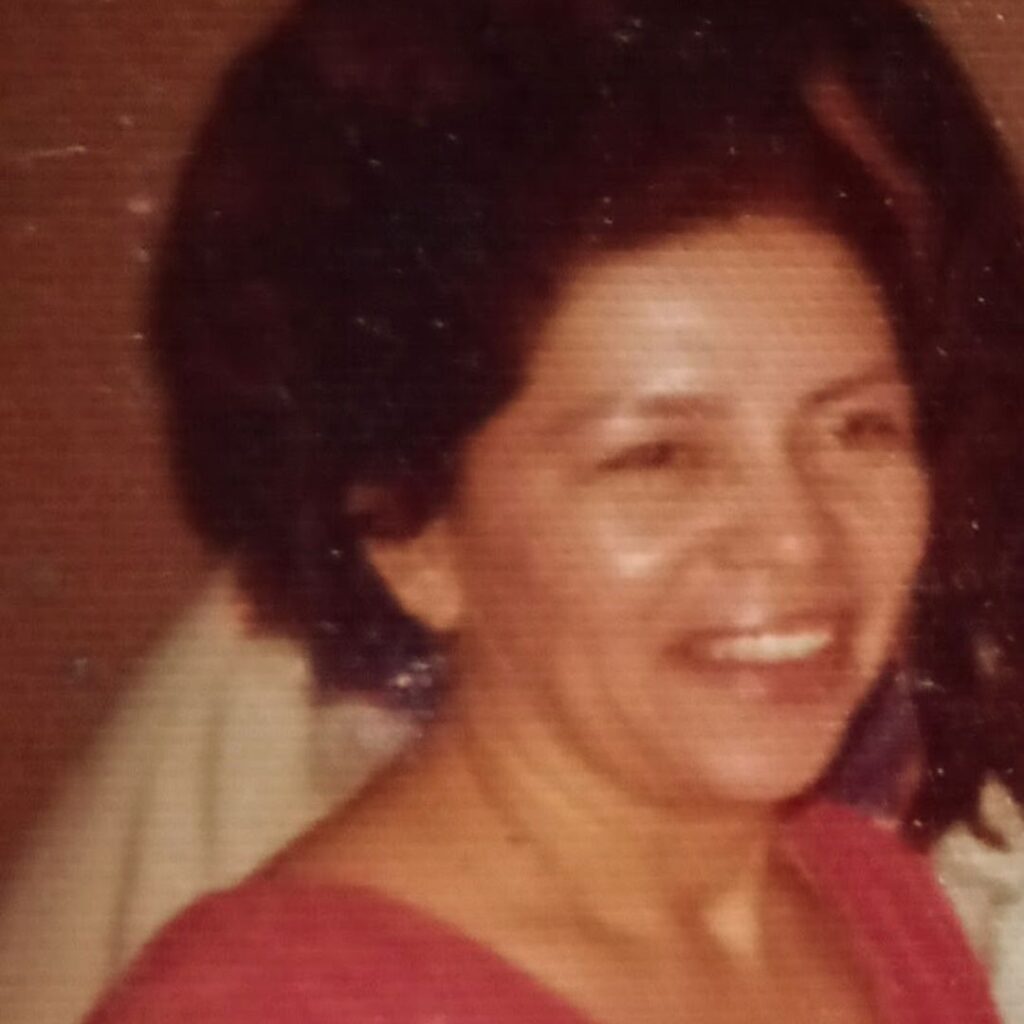Lupe Valtierra Trujillo smiling in a warm, candid moment, wearing a red dress.